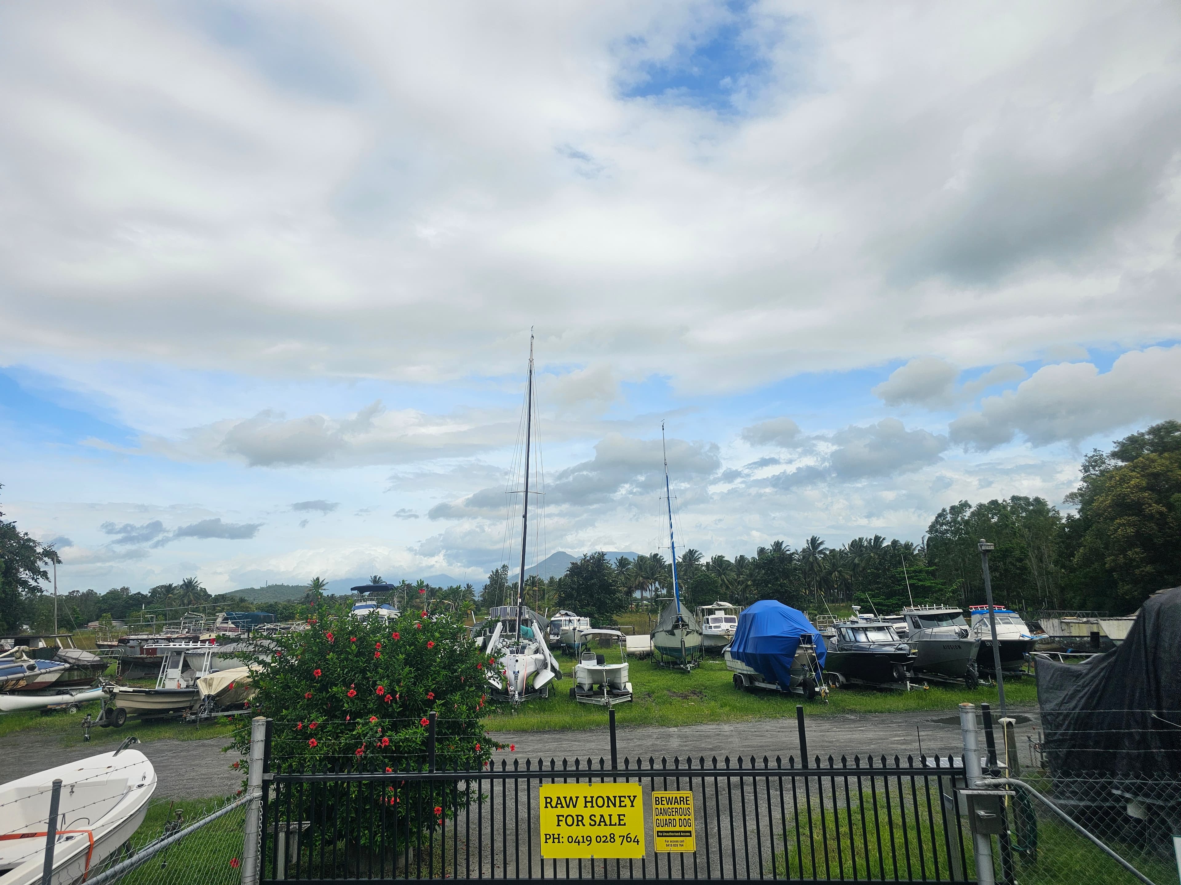 Boats on trailers parked inside the fenced Cairns Boat Storage yard, with mountain ranges behind