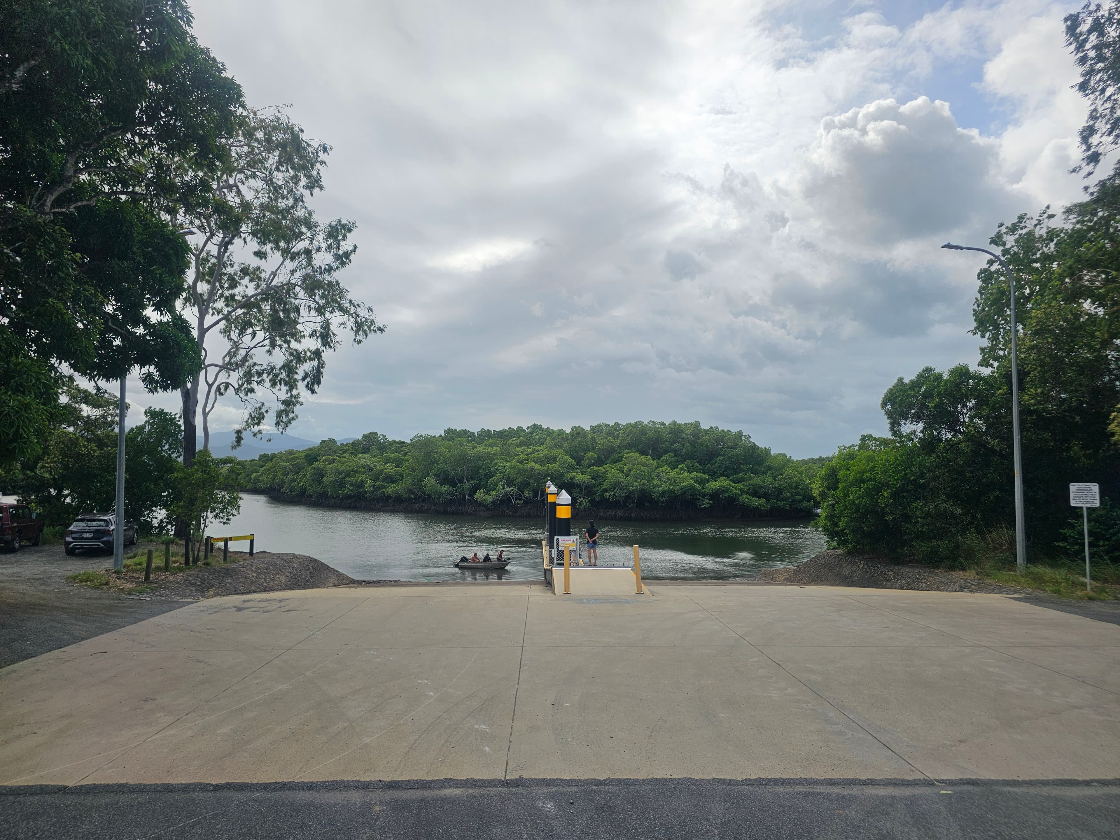 The concrete boat ramp beside the storage yard, leading down to the mangrove-lined inlet
